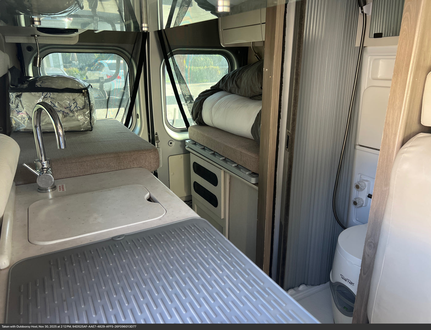 Inside an rv rental: compact kitchen with sink, cozy beds, and a wet bath with toilet & shower.