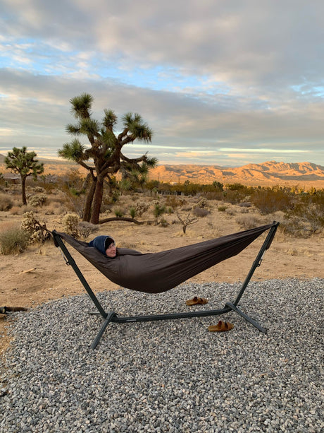 Enjoying a desert sunset in a cozy hammock with Joshua trees. Perfect relaxation spot for your RV rental adventure!