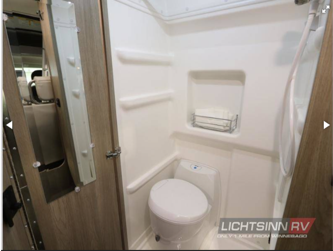 This RV rental features a compact bathroom with a toilet and shower, ideal for travel.