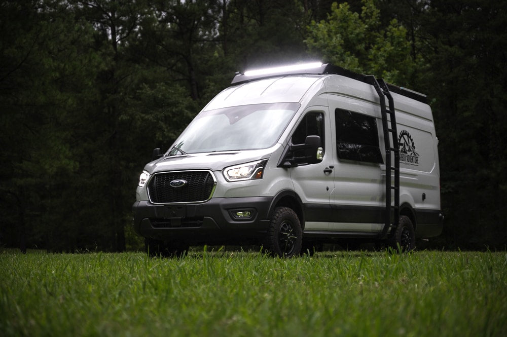 White Ford Transit camper van with bright roof lights & off-road tires