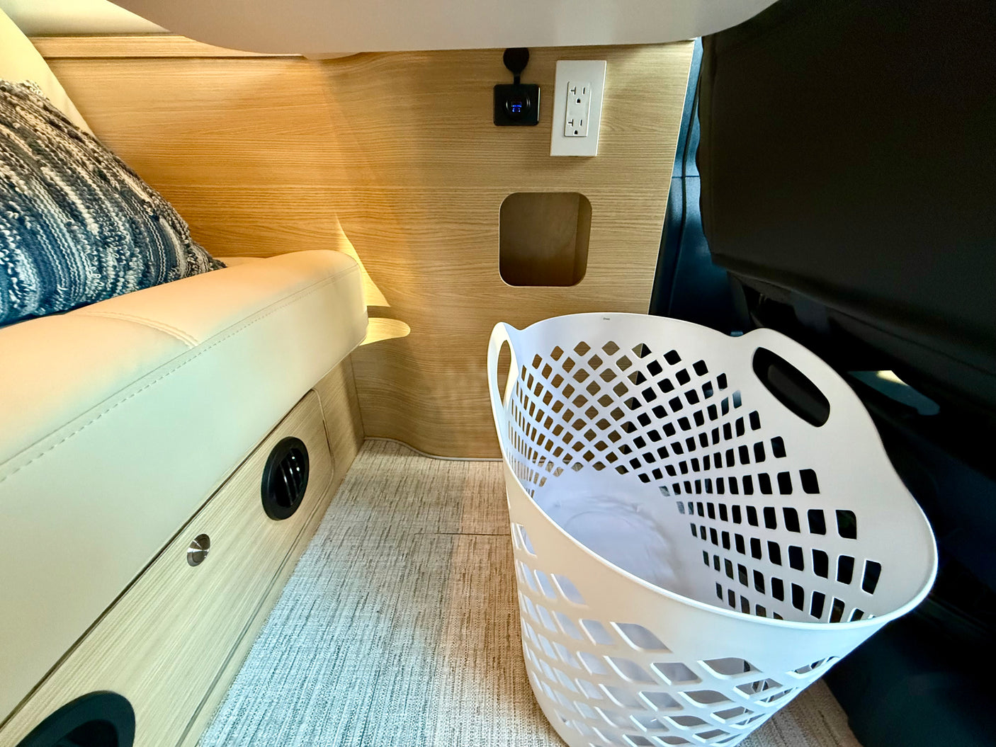 RV rental interior: Cozy seating, wall outlets, control display, vent, and laundry basket.