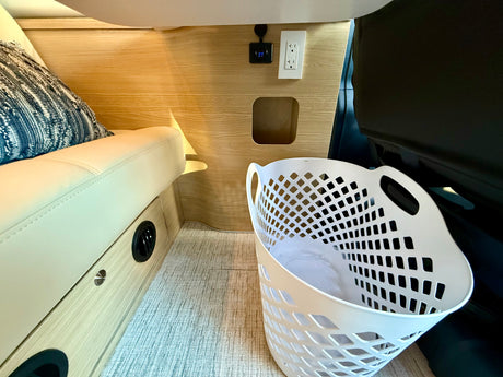 RV rental interior: Cozy seating, wall outlets, control display, vent, and laundry basket.