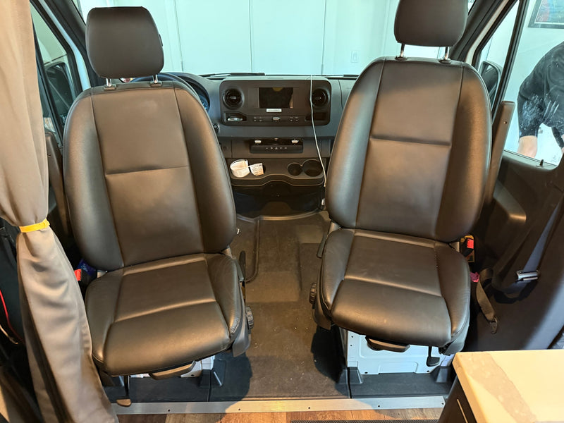 RV rental: Spacious front cabin with comfortable black leather swivel seats for driver and passenger, and the dashboard. — photo 14