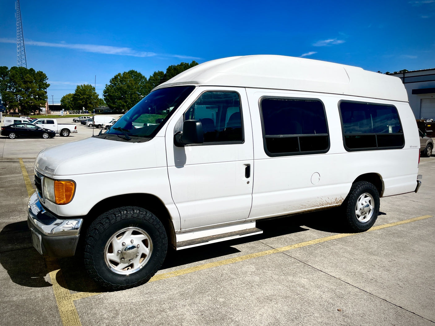 White high-top Ford van, ideal for an rv rental adventure, parked on asphalt under a blue sky.