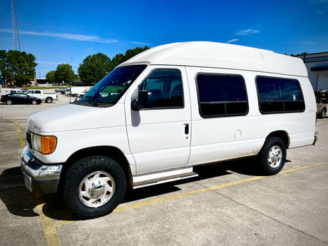 White high-top Ford van, ideal for an rv rental adventure, parked on asphalt under a blue sky.