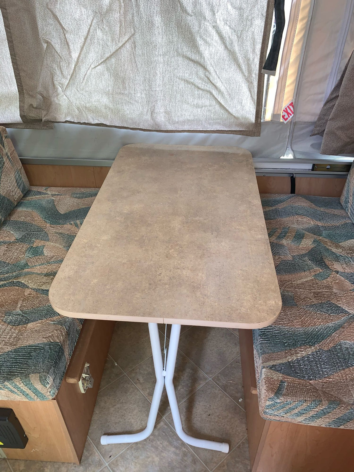This RV rental's dinette features a removable table between two patterned bench seats, under canvas pop-up walls. — photo 9