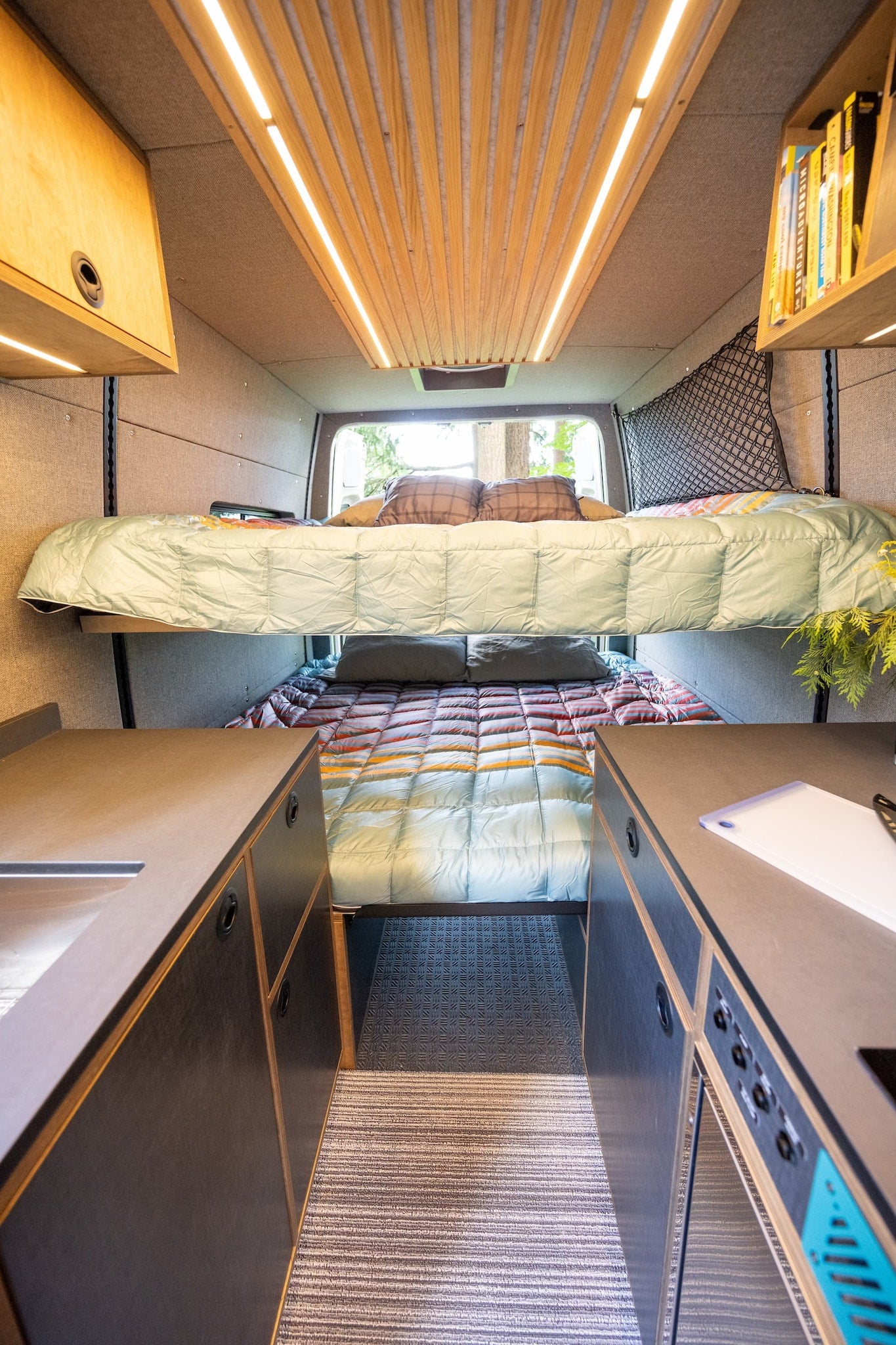 Spacious RV rental interior features sleek bunk beds, ambient ceiling lights, and functional kitchen counters in a modern camper van. — photo 18