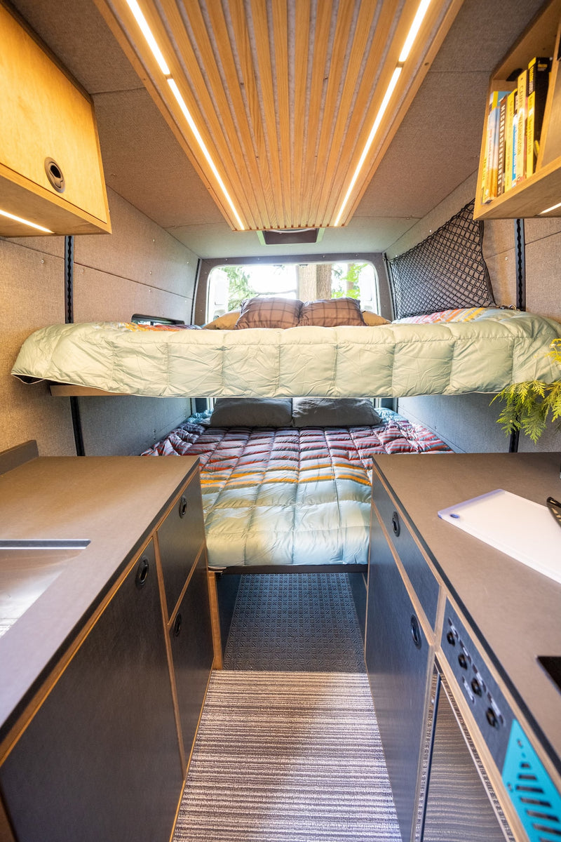 Spacious RV rental interior features sleek bunk beds, ambient ceiling lights, and functional kitchen counters in a modern camper van. — photo 18