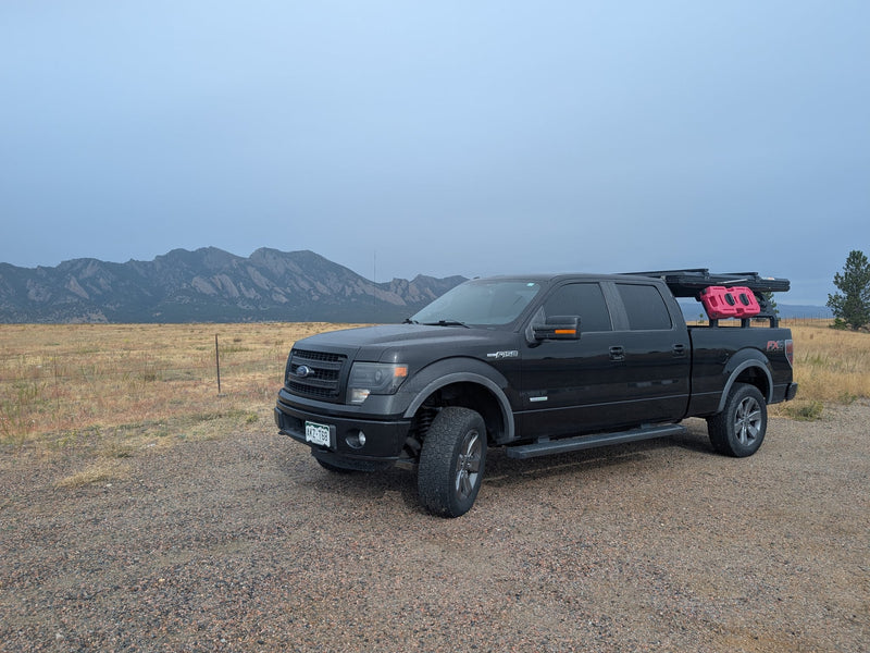  and padded ceiling.|This robust truck camping setup with a Roofnest rooftop tent provides an alternative to an rv rental for outdoor overlanding adventures.|Black Ford F-150 adventure truck with rooftop tent and gear on a gravel road. Perfect rv rental for rugged mountain expeditions.|ROOFNEST cargo on an RV rental — photo 6