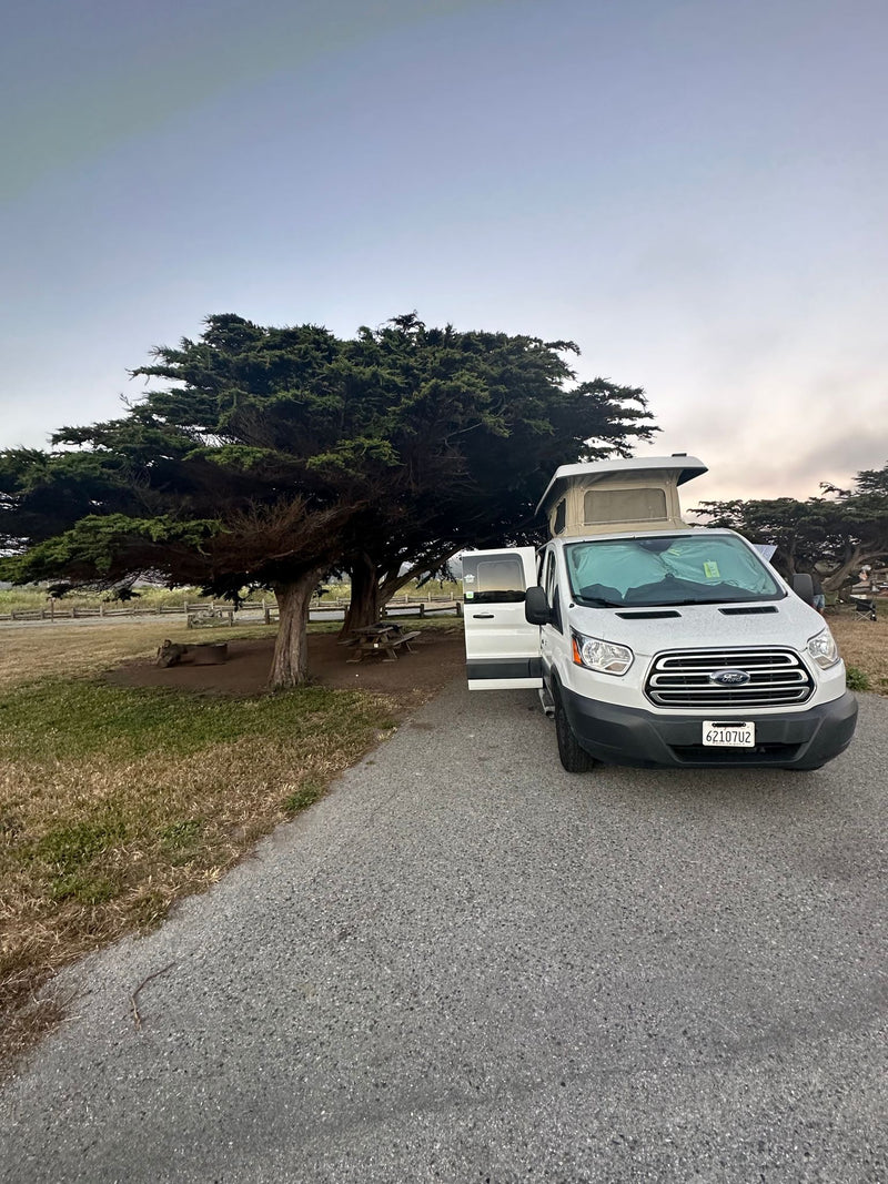  at a bright RV park with other vehicles.|A white pop-top RV rental glows at night — photo 4