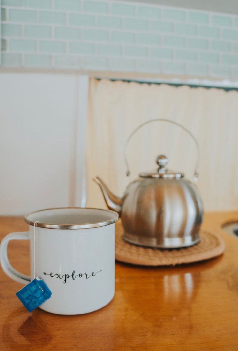 An RV rental's cozy kitchen features a white "explore" mug with a tea bag and a stainless steel kettle. — photo 20