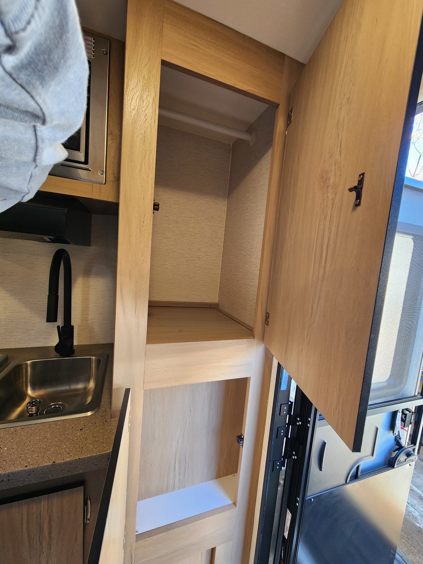 RV rental interior: A practical kitchen with sink and microwave, plus ample open closet storage space.