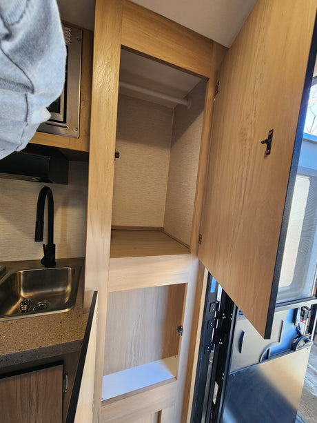 RV rental interior: A practical kitchen with sink and microwave, plus ample open closet storage space.