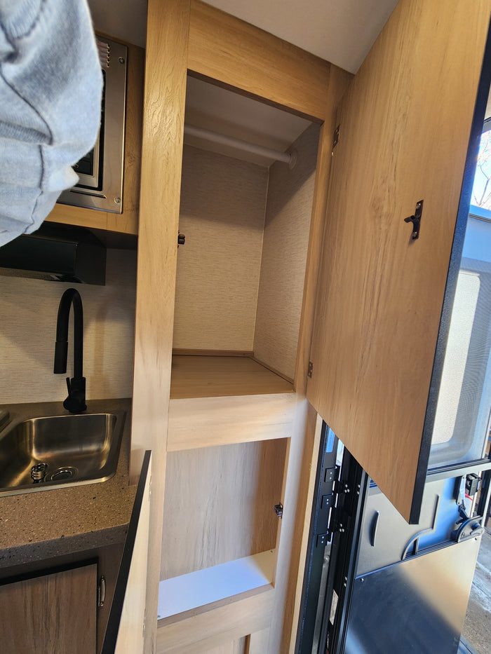 RV rental interior: A practical kitchen with sink and microwave, plus ample open closet storage space.
