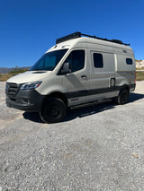 Winnebago Revel camper van, ideal rv rental for adventure, parked on gravel under a clear sky.