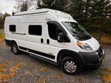 White Winnebago Solis RV rental van, ideal for nature travel. Parked on gravel among autumn trees.