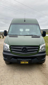 Front view of a military-green Mercedes-Benz Sprinter van, an rv rental, on a dirt path.