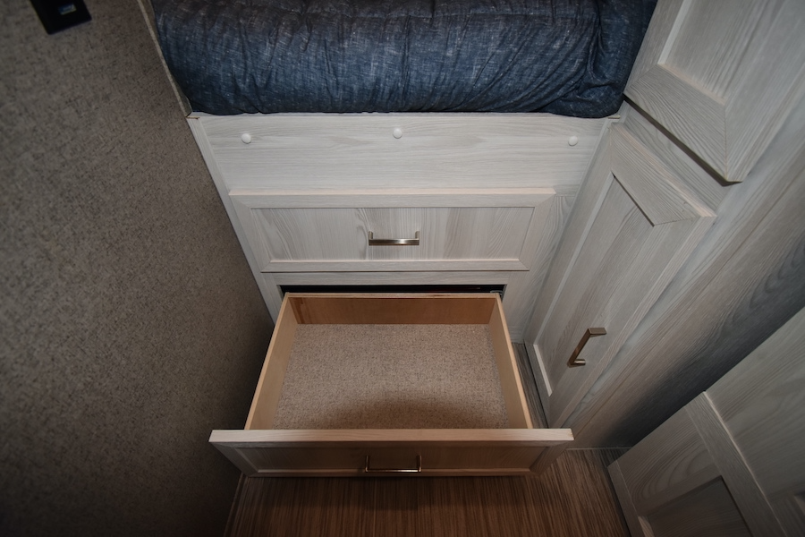 RV rental interior: Light wood cabinetry with an open storage drawer below a bed, revealing functional storage space.