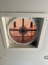 Overhead view of an RV rental ceiling vent fan, displaying its protective mesh, fan blades, and function controls.