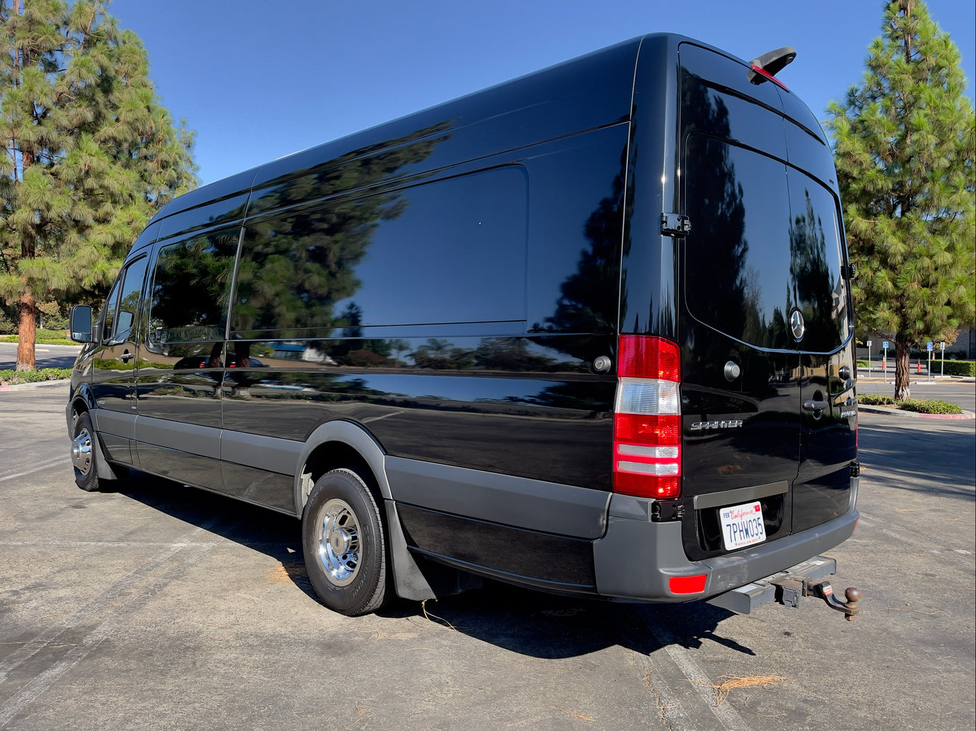 Sleek black Mercedes-Benz Sprinter van with tinted windows, perfect for an RV rental adventure. Parked outside.