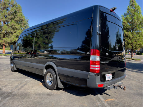 Sleek black Mercedes-Benz Sprinter van with tinted windows, perfect for an RV rental adventure. Parked outside.
