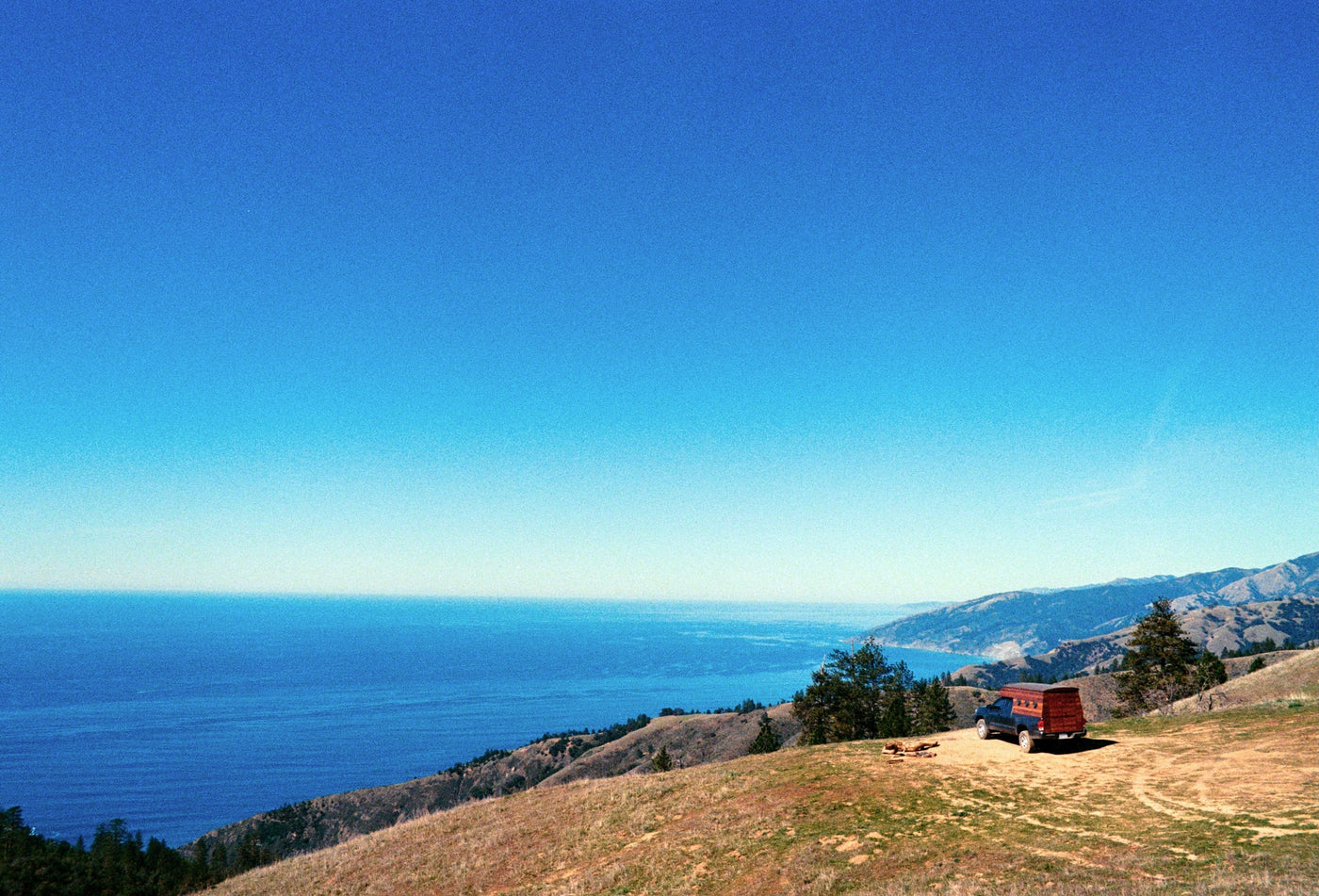 and a plant.|Experience epic scenic drives with our RV rental! A camper truck navigates winding dirt roads on rolling hills — photo 7