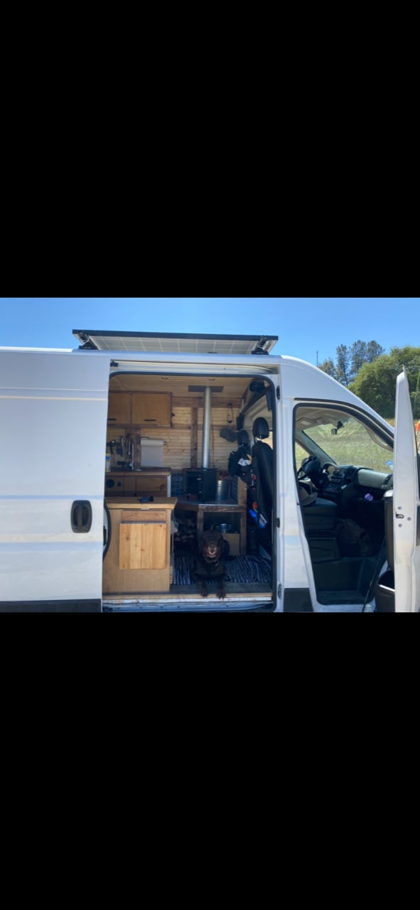  with a small table & outdoor cooking setup.|Experience van life! This cozy RV rental interior features a bed — photo 5