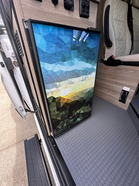 RV rental: Inside a camper van with an artistic fridge, plush seat, and textured floor.