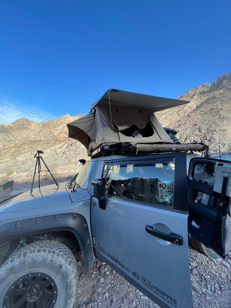 Off-road SUV with a rooftop tent deployed in desert mountains, offering an adventurous alternative to an RV rental.