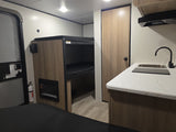 Explore this RV rental's interior: bunk beds, modern kitchenette with sink, and a built-in fireplace for comfort.