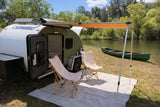 Experience tranquil camping with this RV rental! A teardrop camper, awning, chairs, and canoe beside a scenic lake await your adventure.