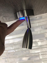 Finger activates a blue-lit touch control for an adjustable reading light, often found in an RV rental.