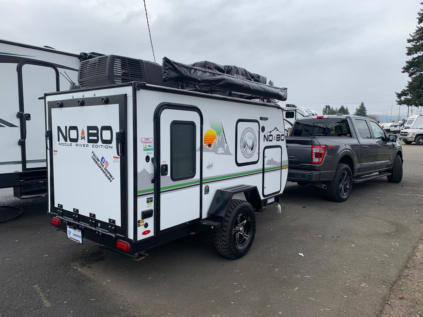 White NOBO Rogue River Edition travel trailer with rooftop tent hitched to a gray Ford F-150 FX4, ideal for rv rental.