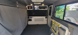 Interior of an RV rental: functional space with sleeping area, storage, small TV, controls, and window views. Perfect for travel.