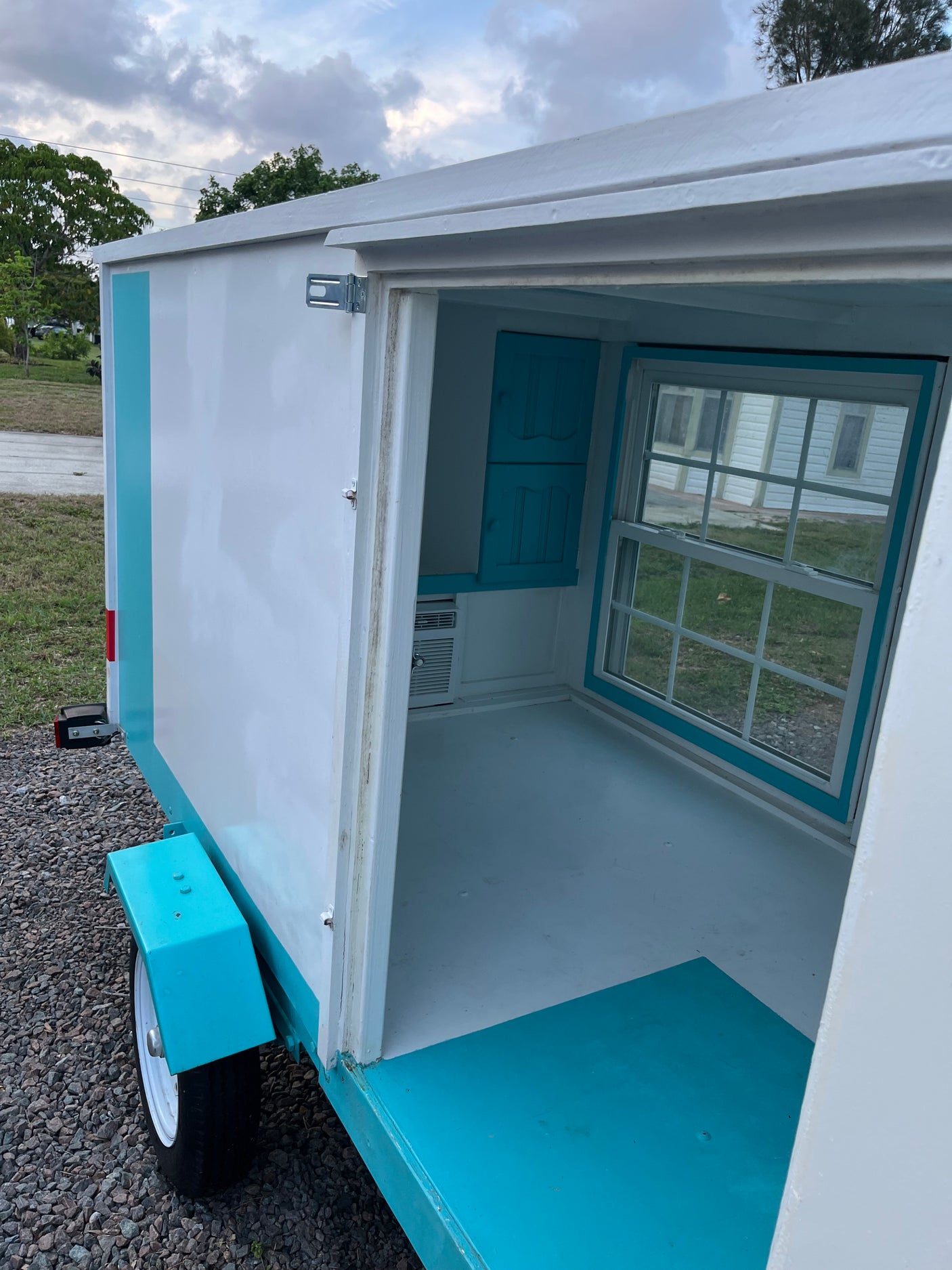 Cozy, compact RV rental: See inside this charming tiny camper, featuring a window, cabinets, and a mini AC unit.