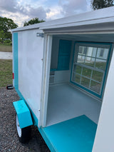 Cozy, compact RV rental: See inside this charming tiny camper, featuring a window, cabinets, and a mini AC unit.
