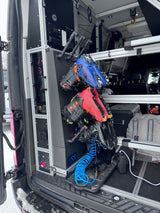 This rv rental van interior features a custom boot dryer/storage system with blue and red ski boots, control panel, and air hose.