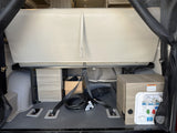 RV rental's rear cargo: Folded bed, organized power cable, and water utility panel (with warning) ensure readiness for adventure.