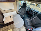 RV rental interior featuring the front cabin with swiveling driver/passenger seats, a small table, and a comfortable bench seat.