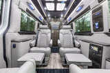 Plush grey captain's chairs with footrests in a luxurious RV rental van's interior, featuring wood flooring and ambient lighting.