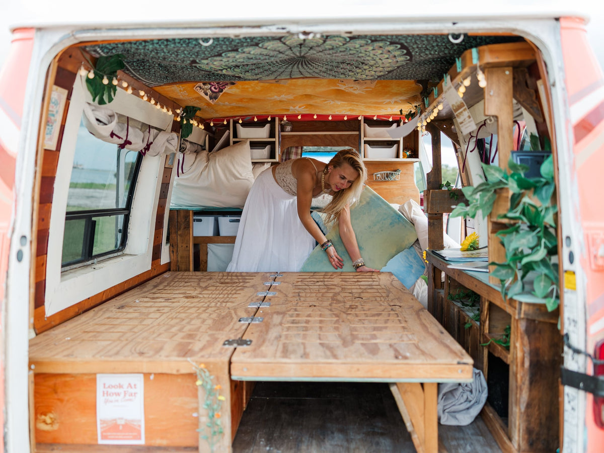  with a sunflower nearby.|A smiling woman points to an open wooden storage box within a cozy RV rental — photo 10