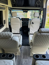Luxury RV rental interior with cream quilted seats, wood flooring, and Mercedes-Benz dashboard. Modern, spacious van.