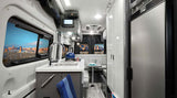 Modern RV rental interior with compact kitchen, dining area, and large window showcasing a desert view. Ready for adventure.