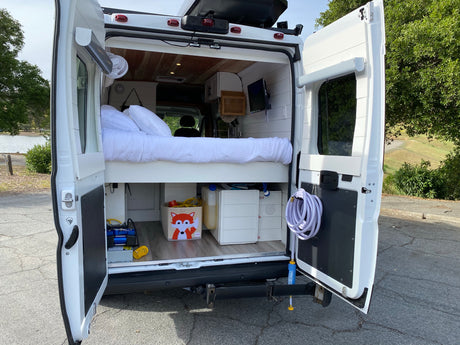 This RV rental's rear interior reveals a cozy bed, mini kitchen, and storage, perfect for mobile adventures.