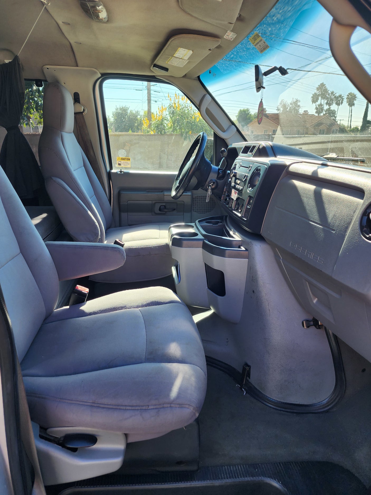 RV rental Ford E-Series van interior: front seats, dashboard, steering wheel, and console, ready for adventure.