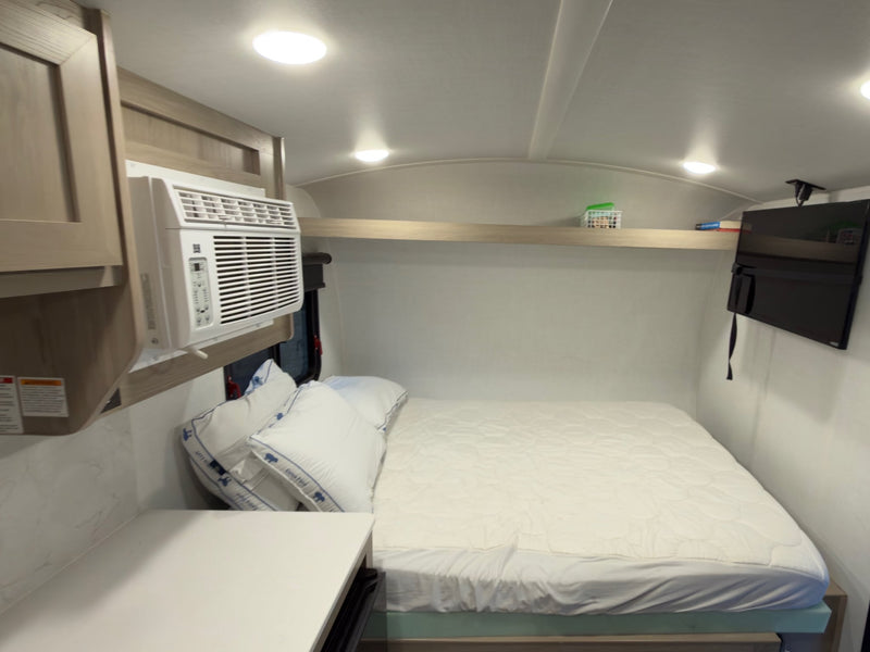  and tinted windows.|Cozy RV rental interior featuring a bed with gray plaid bedding — photo 7