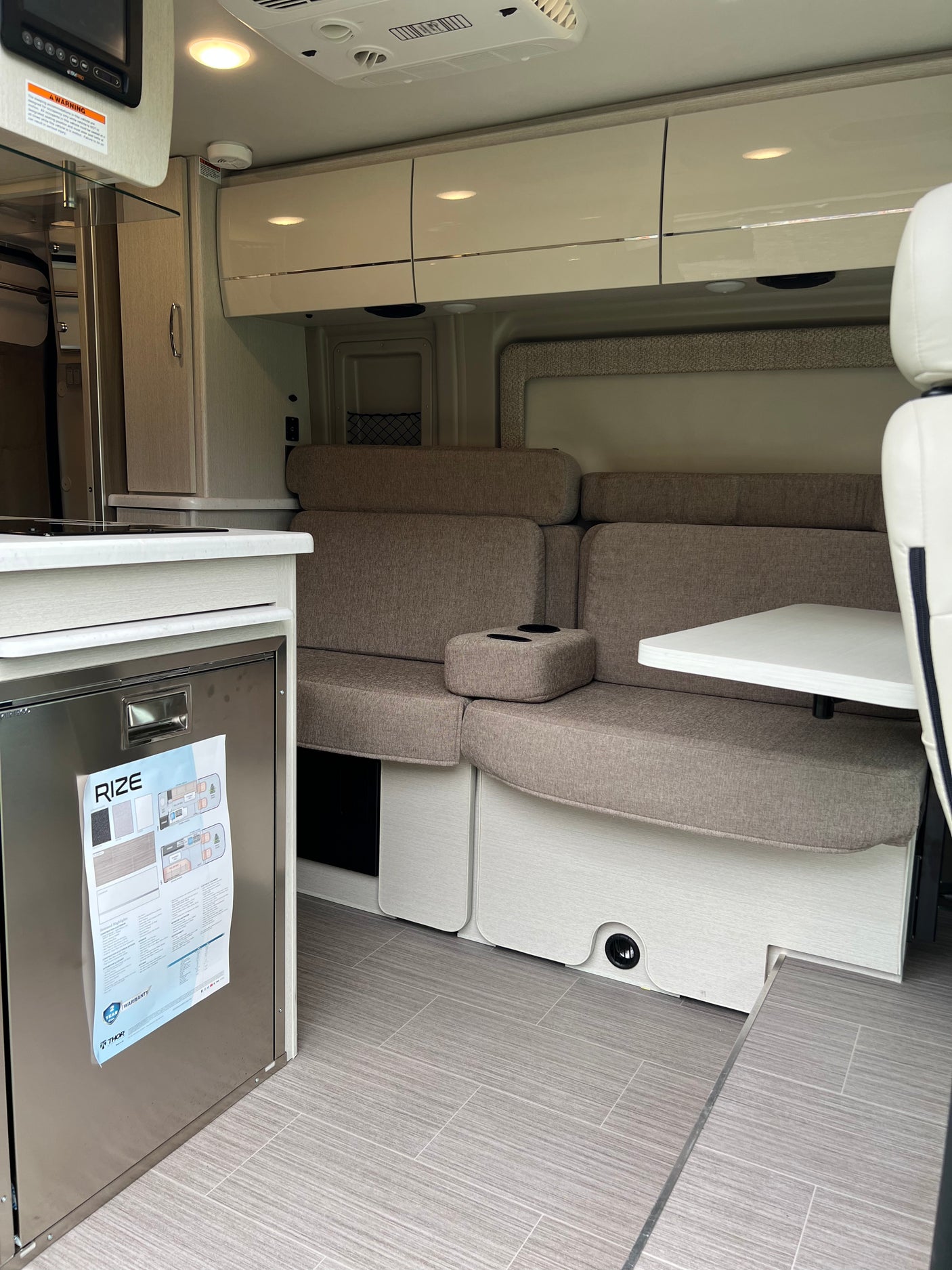 RV rental: Bright interior featuring a compact kitchen, modern dinette seating, and overhead cabinets.