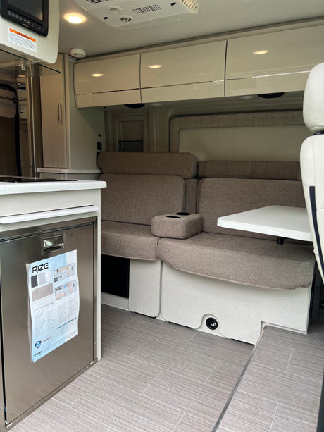 RV rental: Bright interior featuring a compact kitchen, modern dinette seating, and overhead cabinets.