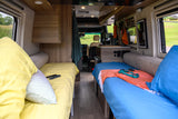 Cozy rv rental interior with twin beds, bright bedding, and compact kitchen. Ideal for a comfortable road trip.