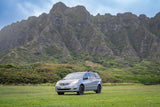Light grey minivan with roof rack, an ideal RV rental alternative for exploring majestic, green mountains and lush landscapes.